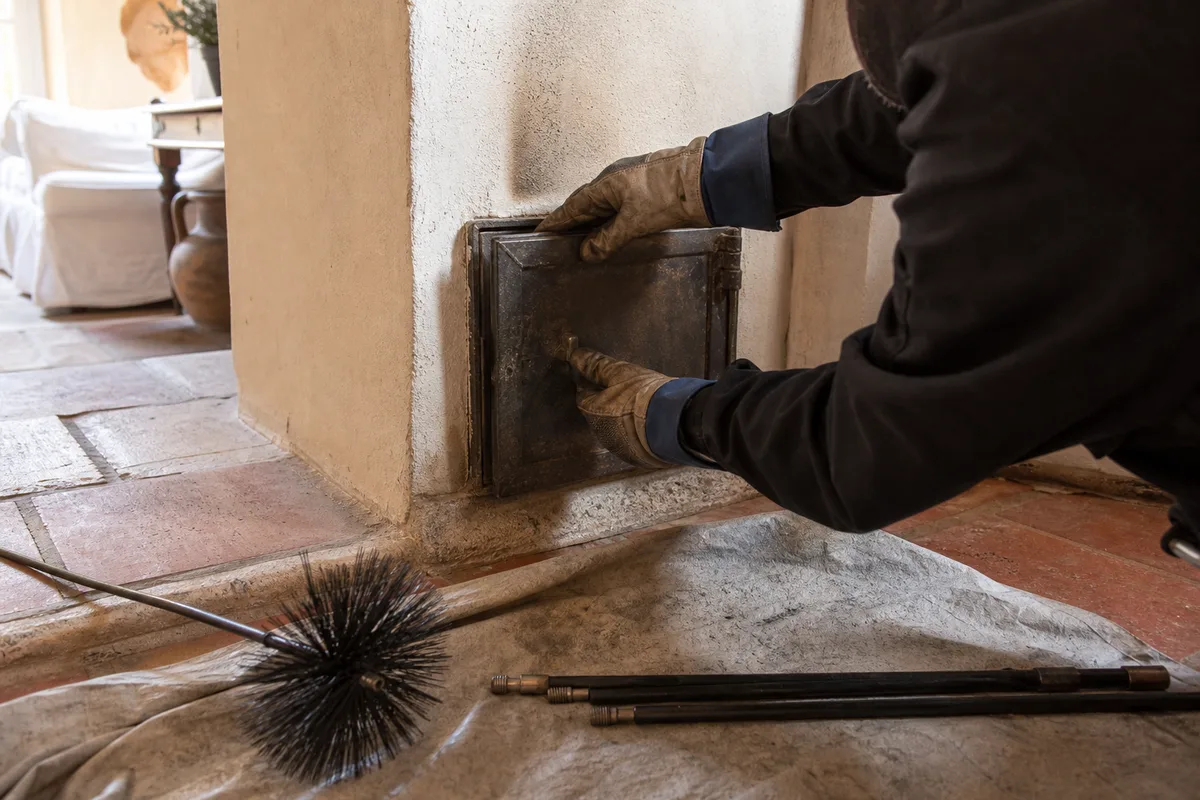 Souche de cheminée maçonnée coiffée d&rsquo;un chapeau métallique sur un toit de tuiles romanes provençal