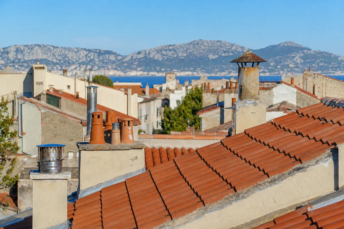 Toits de tuiles romanes et souches de cheminée maçonnées au-dessus du 8e arrondissement de Marseille